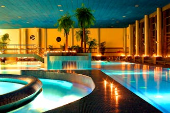 Therme im Wellness Hotel mit Palmen orangenen Licht und schimmerndes klares Wasser - Das Thermenbad bietet viel Platz zum Schwimmen liegen und erholen