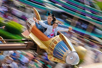 Disneyland Paris Mutter und Tocher in einer der Fahrgeschäfte und Fahren beziehungsweise fliegen mit einer Rakete im Kreis - der Hintergrund ist verschwommen, durch die schnelle Drehung und Bewegung - die Mutter hat die Mini Mouse Ohren auf dem Kopf